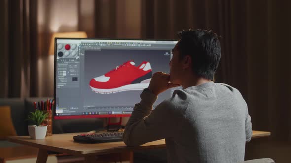 Asian Male Footwear Designer Thinking While Designing Shoe On A Desktop At Home