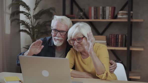 Senior Couple Sitting at Table and Using Laptop During Video Call at Home