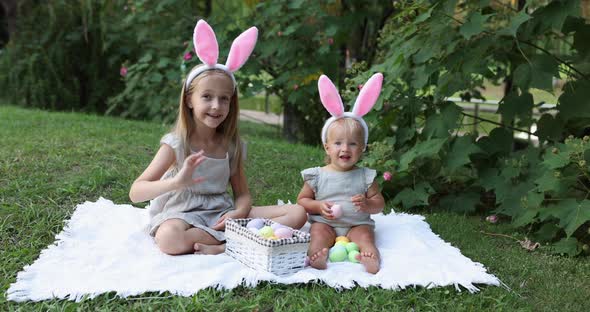 Two Children Wearing Bunny Ears When Pick Up Painted Easter Egg Hunt In Garden or Park