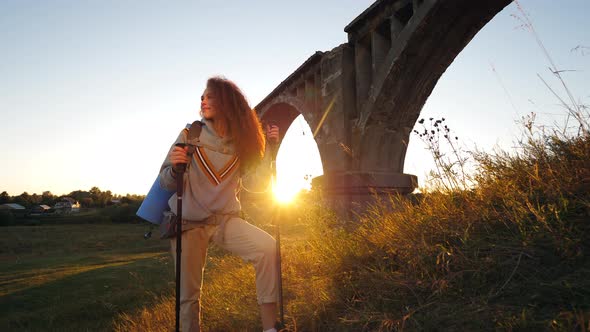 A Lady Is Resting Next To an Old Bridge After Hiking