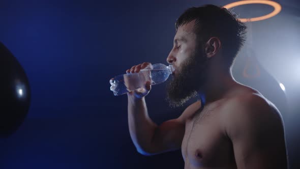 Caucasian Male Athlete Standing in Fitness or Gym Feeling Thirsty Drinking a Bottle of Water After