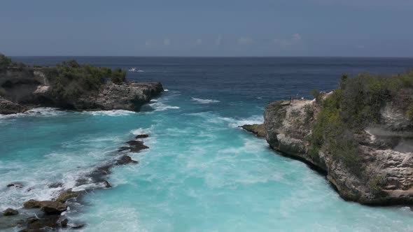 Aerial drone view of ocean waves breaking in a small rocky bay in Indonesia