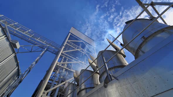 Grain processing plant. Smoke from pipes going into the air of industrial factory. Grain elevator. 