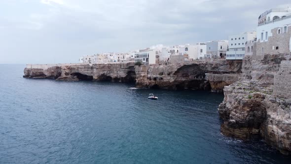 Polignano a mare village, daycruiser boat, caves and cliffs from above