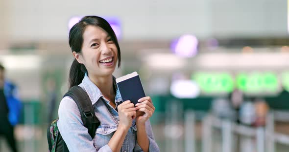 Cheerful woman holding passport at airport