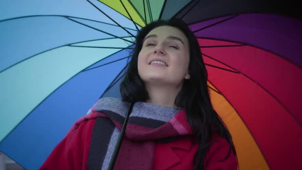 Close-up Portrait of Beautiful Caucasian Girl with Green Eyes Spinning Colorful Umbrella at the