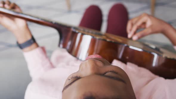 Overhead view of african american woman singing and playing guitar at home