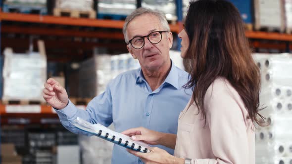 Mature woman and man analyzing documents in the warehouse. Shot with RED helium camera in 8K.