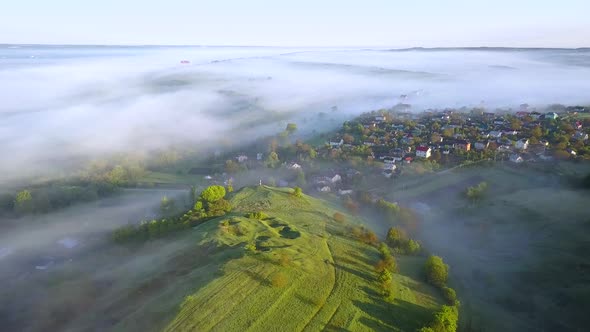 Aerial view of morning for over village houses on green spring hills.