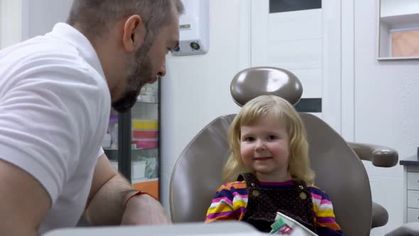 A Cute Little Girl is Learning to Clean Her Teeth on a Plastic Jaw Model