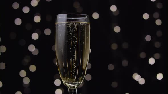 Glass of Champagne with a Rotating Bubbles Inside. Bokeh Background