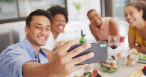 Group of diverse male and female friends taking selfie at dinner party on patio