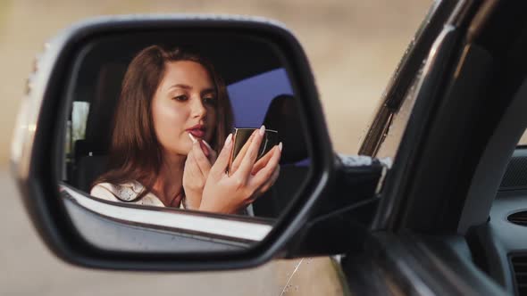 Reflection of Girl in Car Rear View Mirror Who Applying a Lip Gloss and Smiling