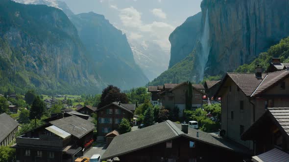 drone flying over rooftops in Swiss mountain valley with waterfall