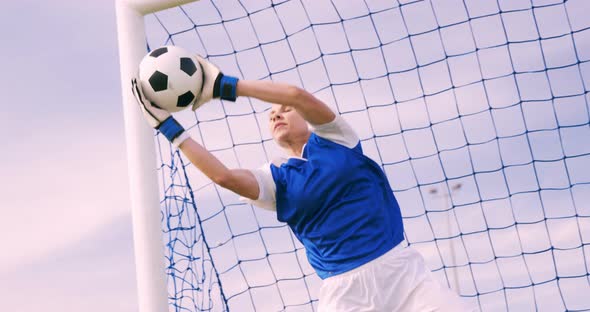 Goalkeeper in blue making a save