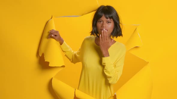 Young Woman Points at Space for Advertisement Over Torn Yellow Paper Background