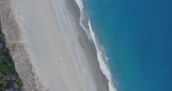 Aerial view waves breaking on the sandy beach