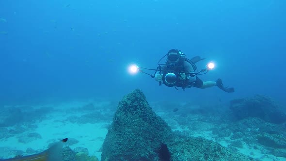 A video of an underwater cameraman filming marine life in the ocean with underwater equipment and li