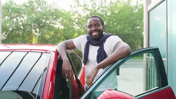 African American Standing Near His Red Car and Looking at Camera with Sincerely Smile in Car Wash