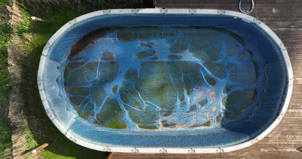 Top down rising aerial of an empty and dirty above ground pool.