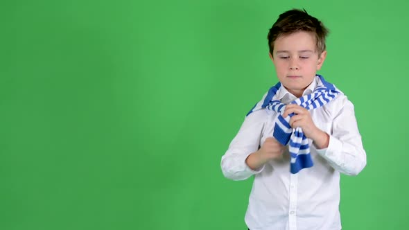 Young Handsome Child Boy Ties a Sweater Around His Neck and Smiles To Camera - Green Screen - Studio