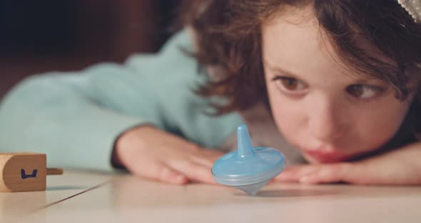 Close up shot of a girl spinning a Hanukka dreidel on the floor