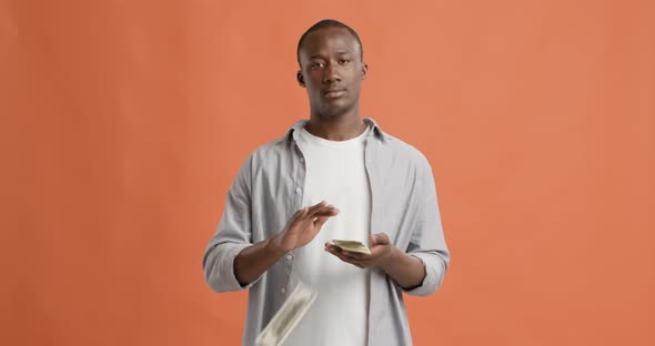Serious Black Man Throwing Money, Orange Background