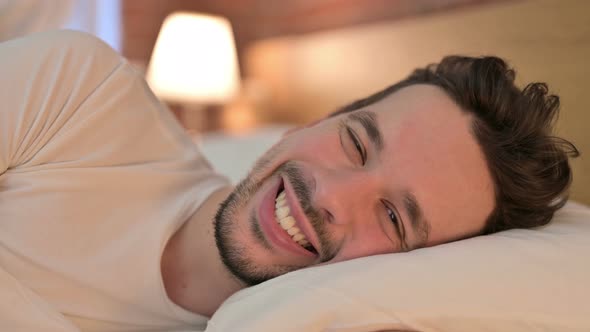 Portrait of Young Man Smiling and Looking at Camera in Bed