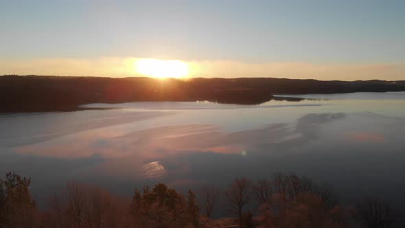 Lake with Golden Sunset and Forest Horizon Aerial Forward