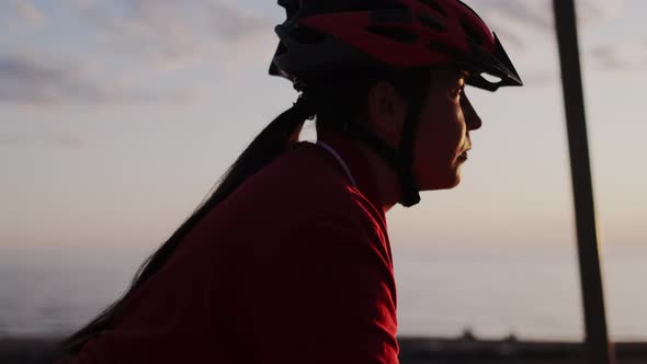 Close of Serious Young Woman Wearing Red Protective Helmet Riding Bicycle