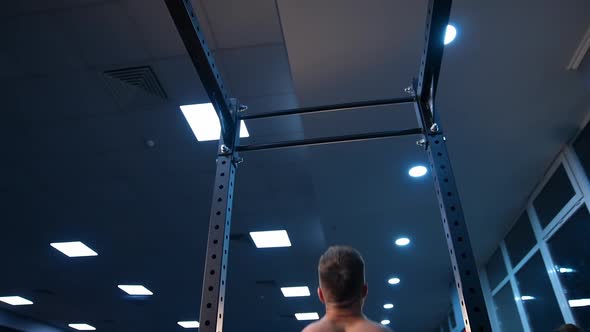 Handsome man gumped on horizontal bar. Male sportsman trains in gym. Slow motion