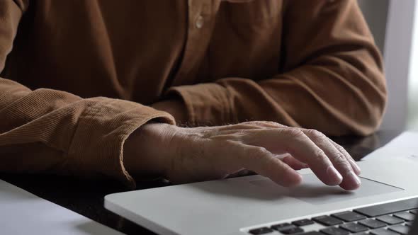 Old man using laptop computer at home.