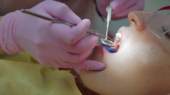 Woman Dentist Treating Teeth To Woman Patient in Clinic. Female Professional Doctor Stomatologist at