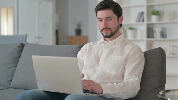 Attractive Young Businessman with Laptop Smiling at the Camera