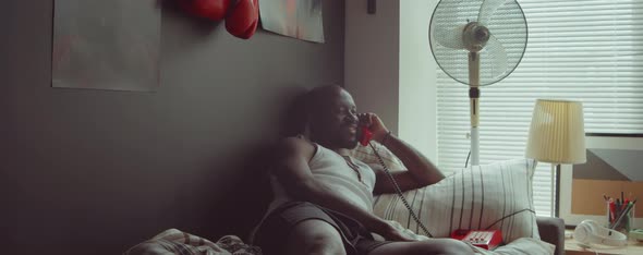 African American Man Talking on Phone on Bed in Morning