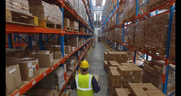 Warehouse worker carrying cardboard box on hoverboard