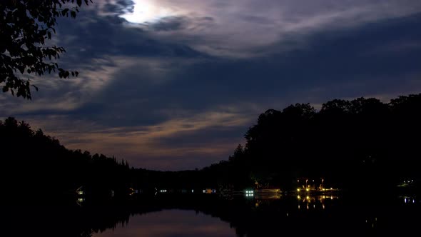 Timelapse of the moon and Mars over lake on a cloudy night