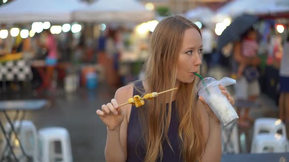 Slowmotion Shot of a a Young Woman Eating Street Food on an Asian Street Market