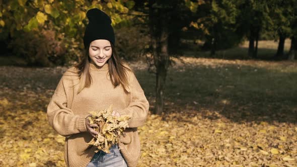 Carefree Young Girl Playing with Autumn Leaves and Posing in Park