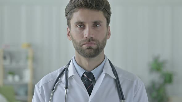 Serious Young Doctor with Beard Looking at Camera