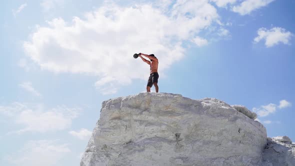 Sportive man with dumbbell. Athletic man doing workout routine on nature