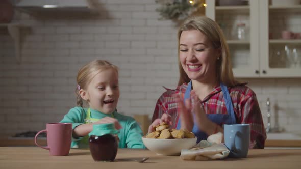 Mom and Child Eating Homemade Cookies in Kitchen