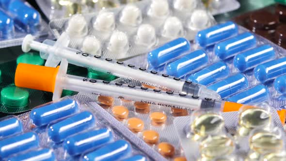 Some Different Contraceptive Pills and Two Syringes, Rotation, Reflection, Close Up