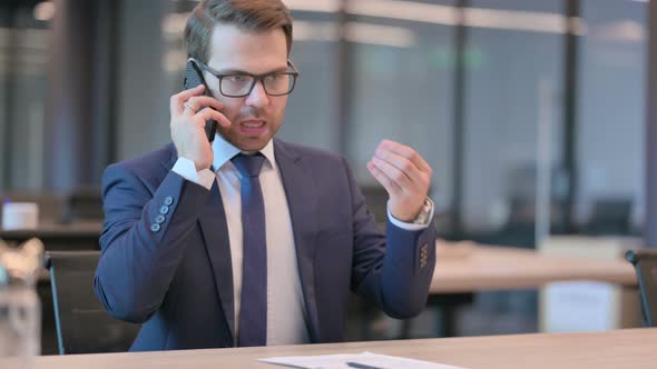 Angry Businessman Talking on Phone in Office