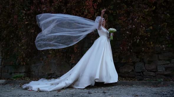 The Bride in a Wedding Dress is Blowing a Strong Wind She is Smiling Sincerely