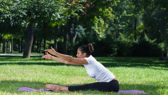 Girl with a Sports Figure Is Engaged in Yoga in Park