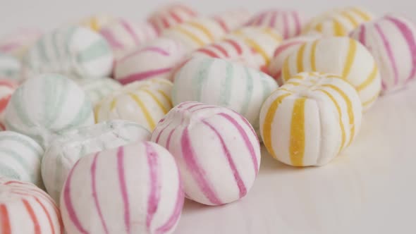 Pile of striped sugar bonbons on white close-up 4K video