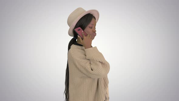 Pretty African American Woman in Knitted Sweater and White Hat Answering Her Phone on Gradient