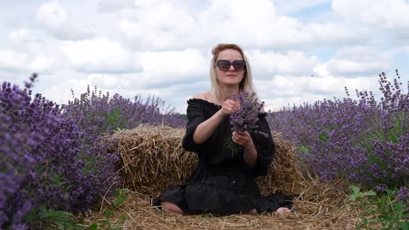 Young caucasian female woman holding violet aromatic flowers in endless lavender field. Slow motion.