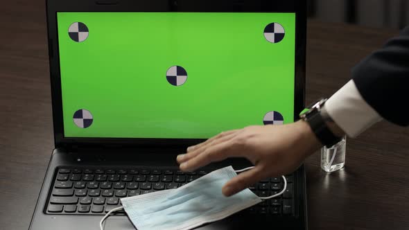 Hand Takes Mask From Laptop with Green Screen, Chroma Key. Coronavirus Covid-19